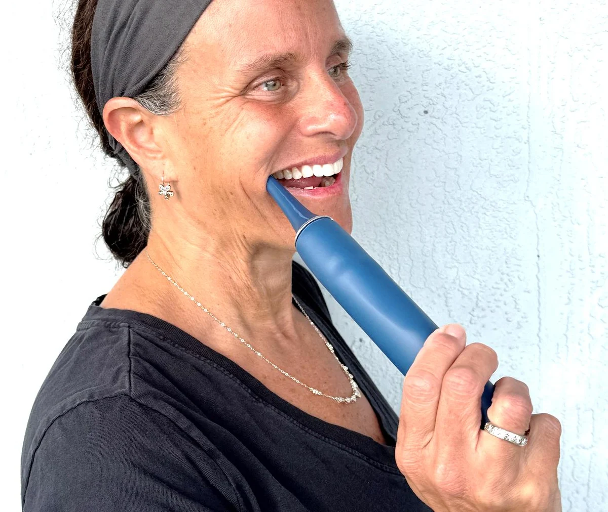 A woman smiling while using the PhysioJaw device inside her mouth
