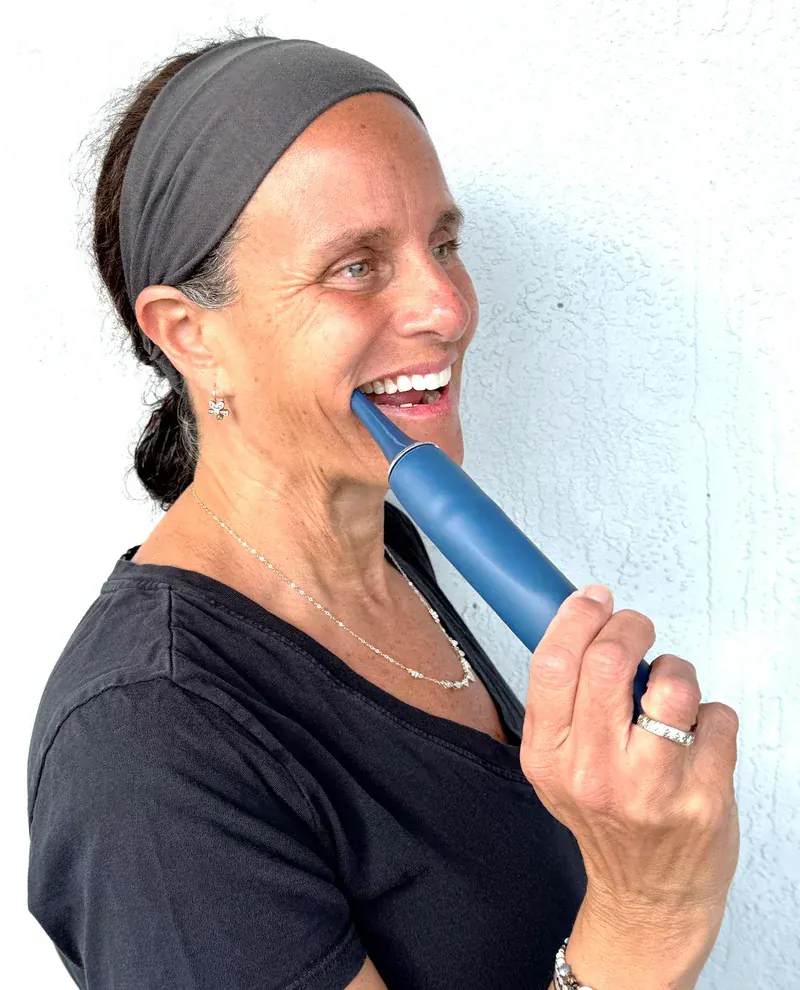 A woman using the PhysioJaw device inside her mouth